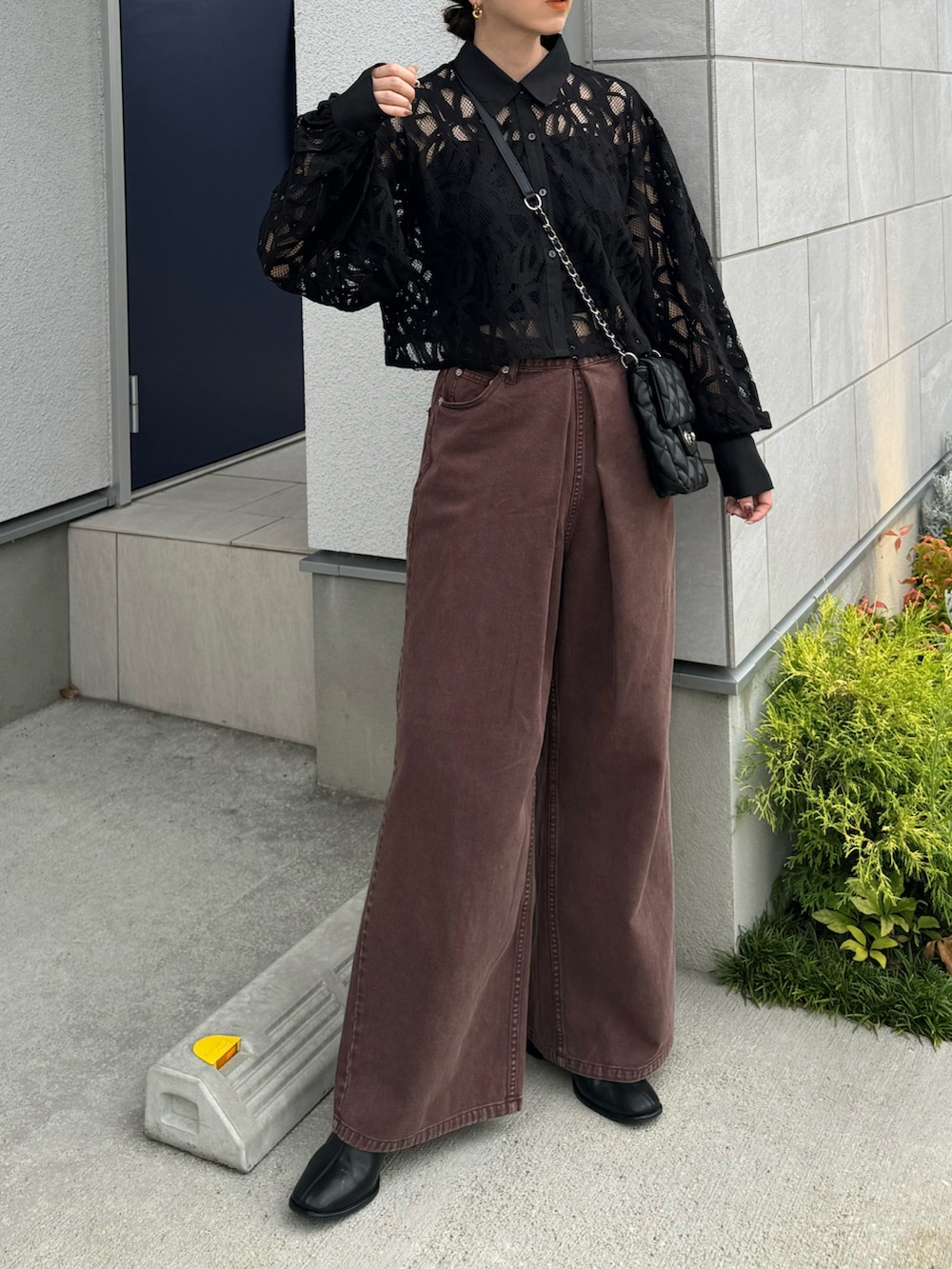 ブラウン系のデニムパンツ、ブラック系のショルダーバッグ、ブラック系のシャツ/ブラウスを着用したレディースの秋コーディネートの2枚目の写真