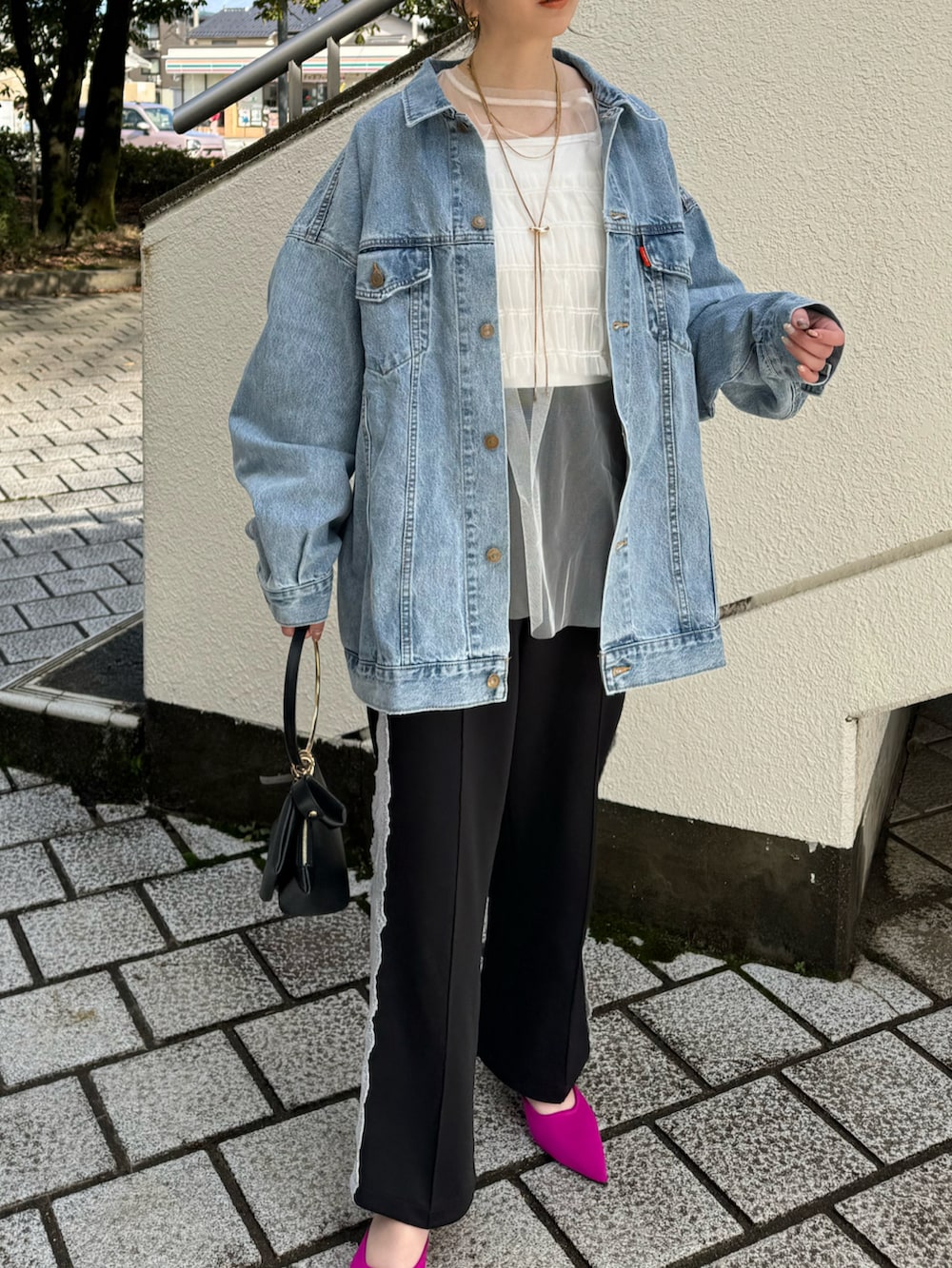 ブルー系のデニムジャケット、ブラック系のその他パンツ、ブラック系のハンドバッグを着用したレディースの冬コーディネートの2枚目の写真