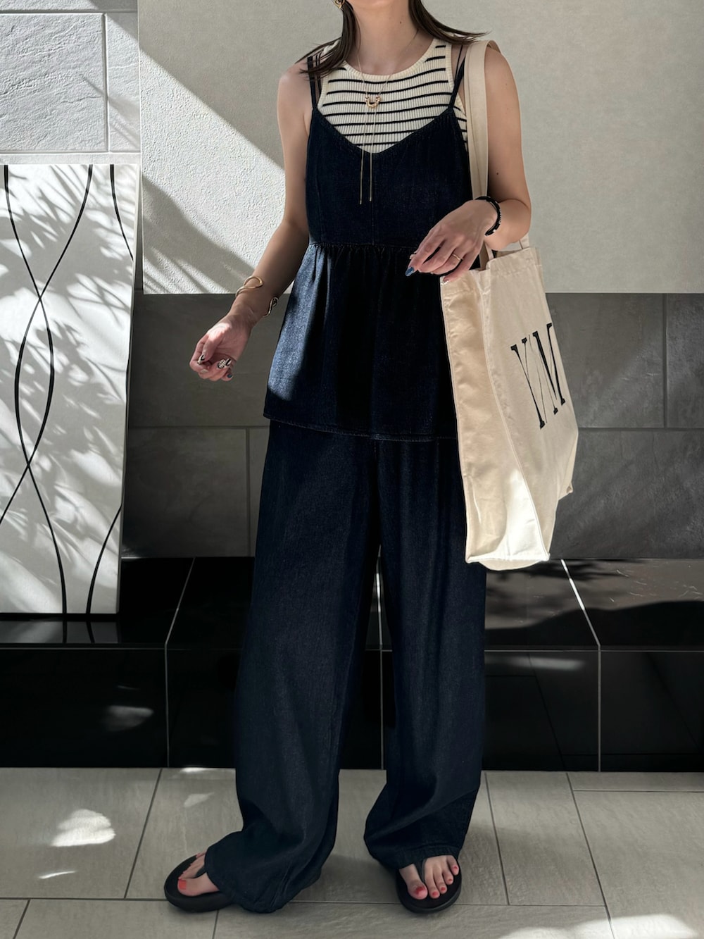 ブルー系のキャミソール、ブルー系のデニムパンツ、ホワイト系のトートバッグを着用したレディースの夏コーディネートの3枚目の写真