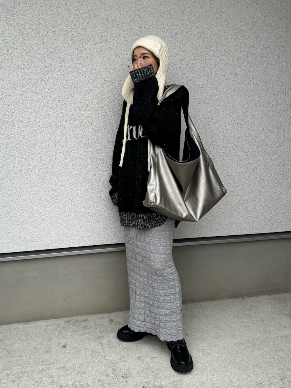 ブラック系のニット/セーター、シルバー系のトートバッグ、ブラック系のブーツを着用したレディースの冬コーディネートの4枚目の写真