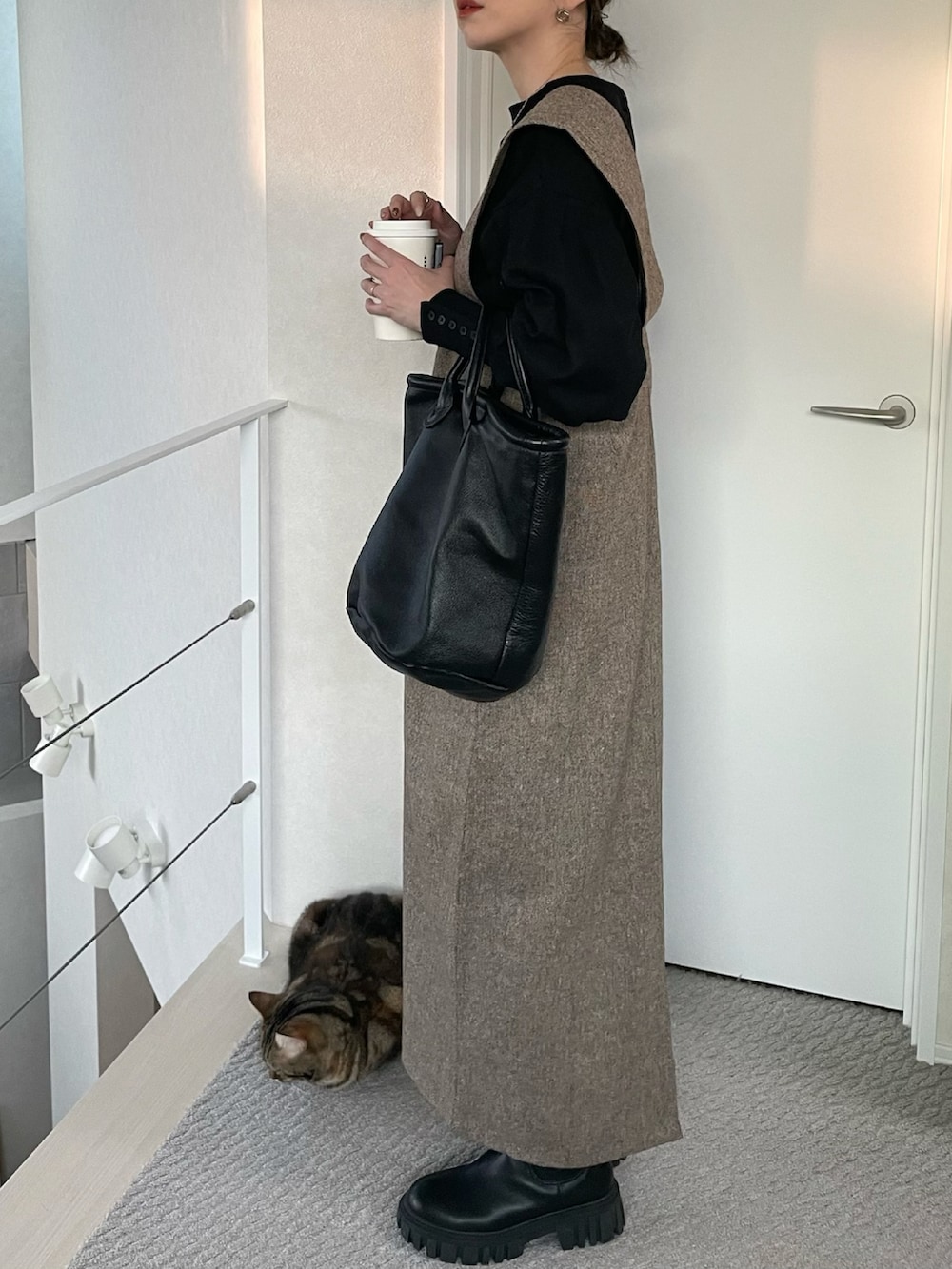 ブラウン系のジャンパースカート、ブラック系のTシャツ/カットソー、ブラック系のブーツを着用したレディースの冬コーディネートの4枚目の写真