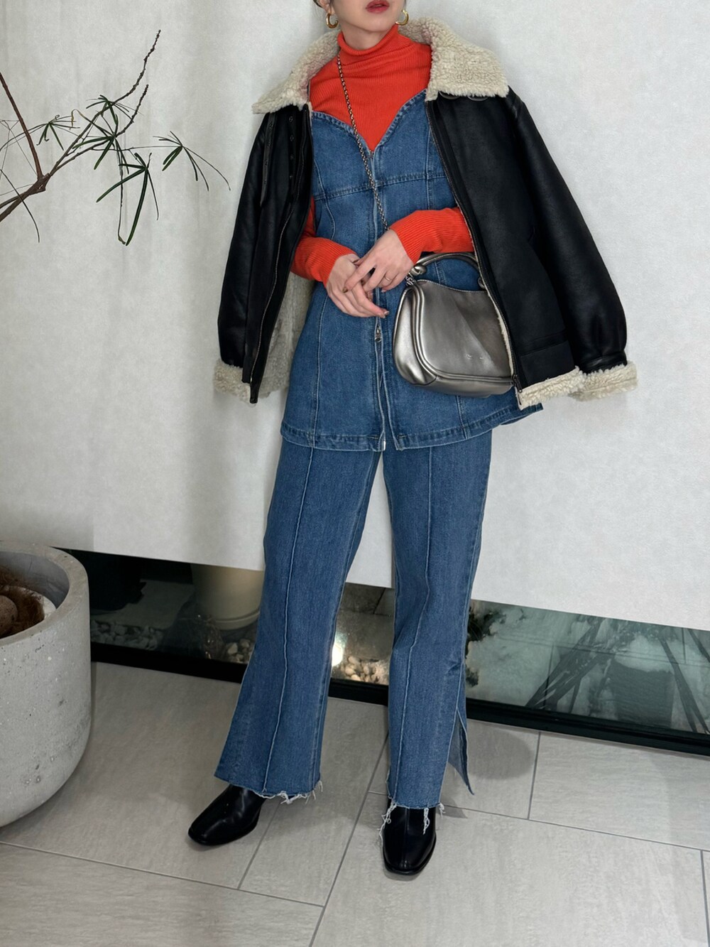 ブルー系のベスト、ブルー系のデニムパンツ、シルバー系のショルダーバッグを着用したレディースの冬コーディネートの4枚目の写真