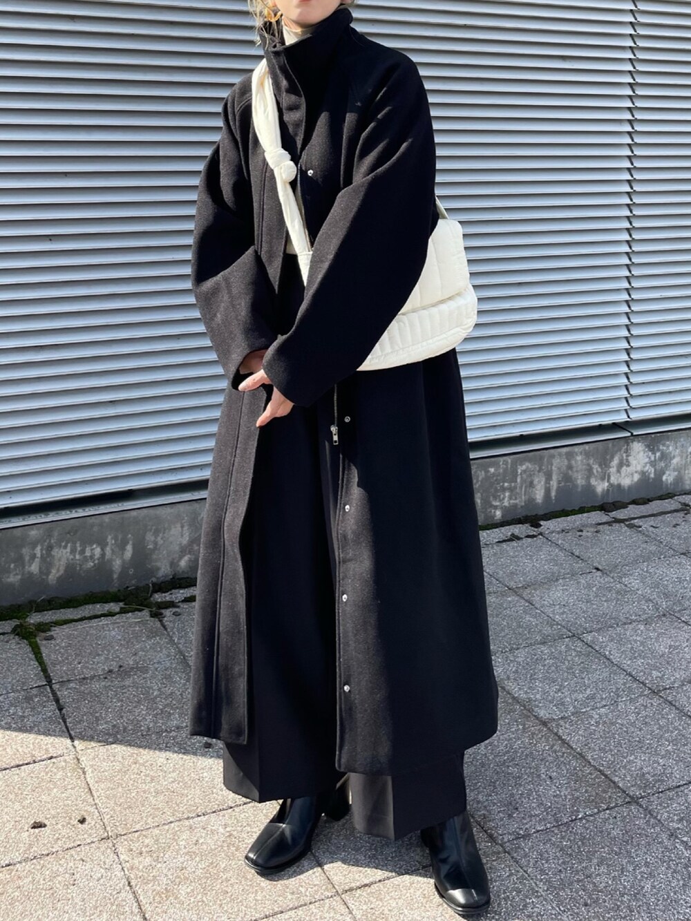 ブラック系のその他アウター、ホワイト系のニット/セーター、ブラック系のその他パンツを着用したレディースの秋コーディネートの2枚目の写真