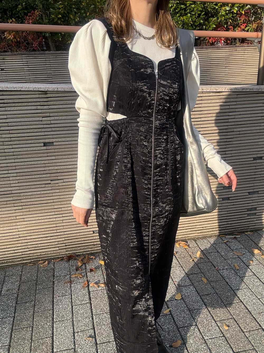 ブラック系のジャンパースカート、ホワイト系のTシャツ/カットソー、ブラック系のブーツを着用したレディースの秋コーディネートの4枚目の写真