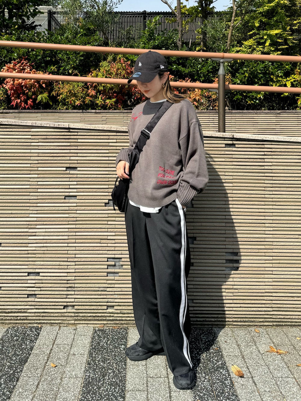 グレー系のニット/セーター、ブラック系のショルダーバッグ、ブラック系のスラックスを着用したレディースの秋コーディネートの2枚目の写真