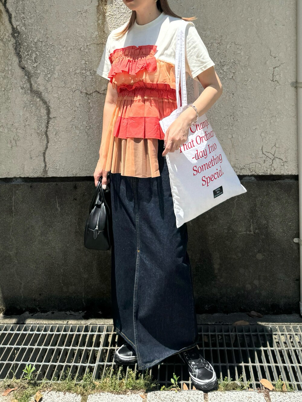 オレンジ系のTシャツ/カットソー、ブルー系のデニムスカート、ブラック系のスニーカーを着用したレディースの夏コーディネートの2枚目の写真