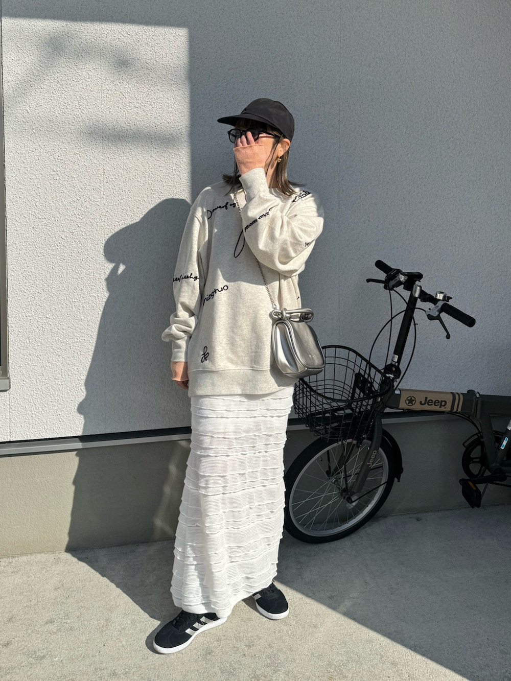 ホワイト系のスウェット、ホワイト系のスカート、ブラック系のスニーカーを着用したレディースの春コーディネートの2枚目の写真