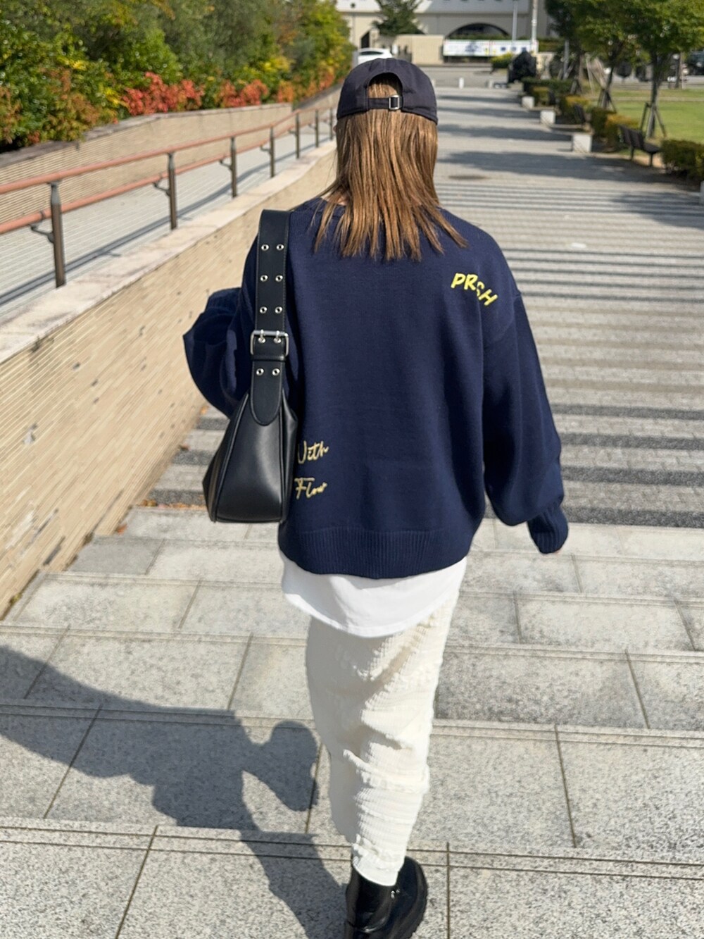 ホワイト系のスカート、ブルー系のニット/セーター、ブラック系のハンドバッグを着用したレディースの秋コーディネートの3枚目の写真