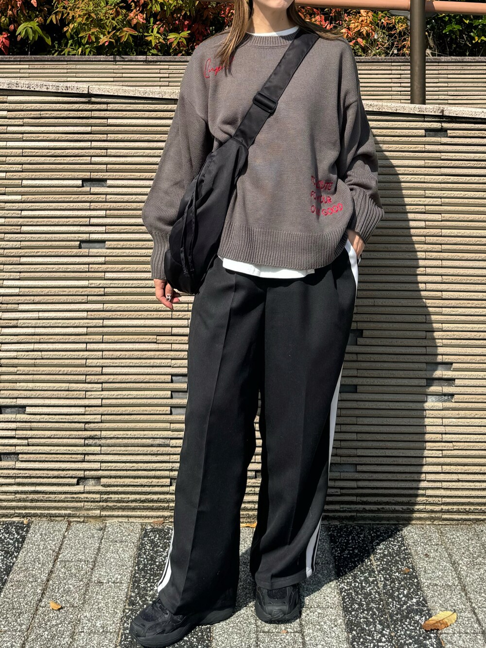 グレー系のニット/セーター、ブラック系のショルダーバッグ、ブラック系のスラックスを着用したレディースの秋コーディネートの3枚目の写真