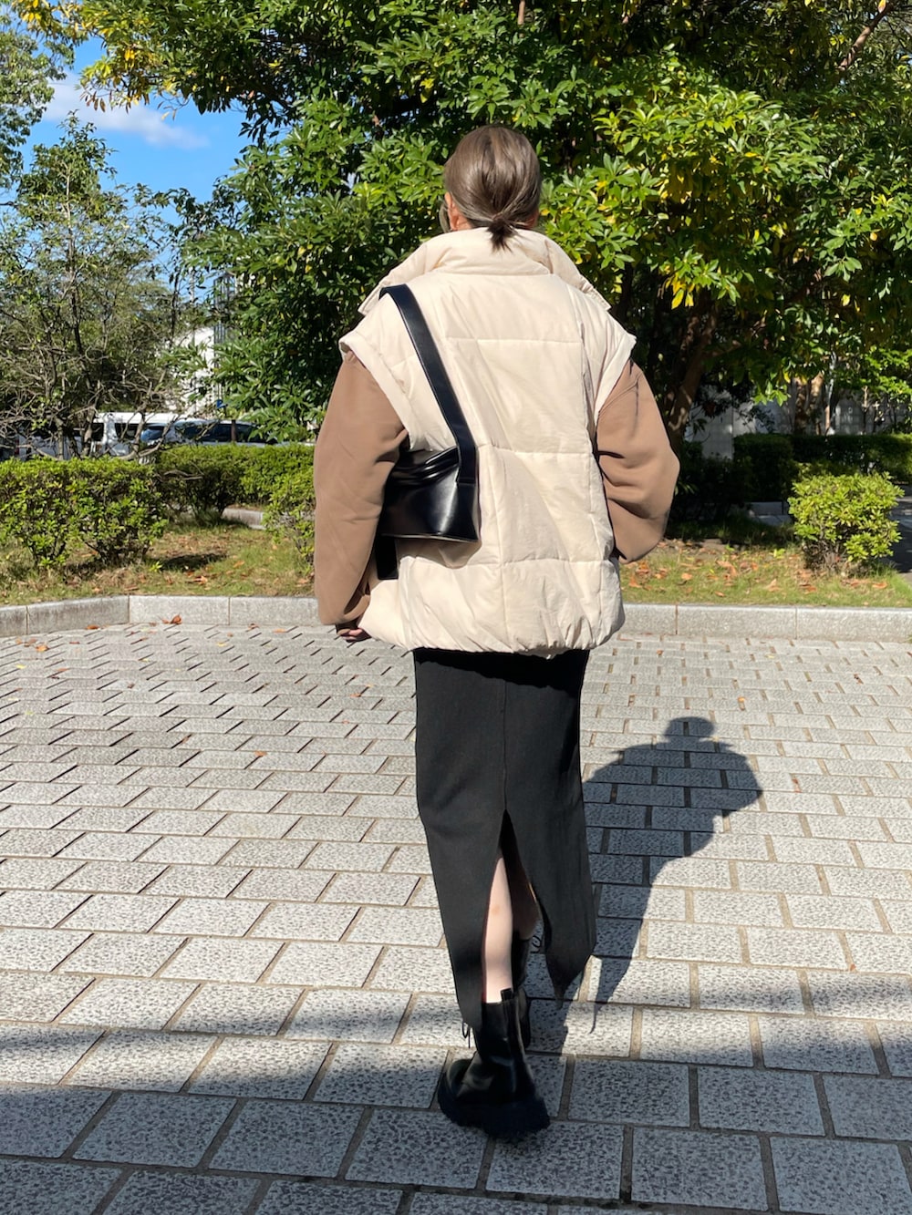 ホワイト系のその他アウター、ブラック系のスカート、ブラック系のブーツを着用したレディースの秋コーディネートの4枚目の写真