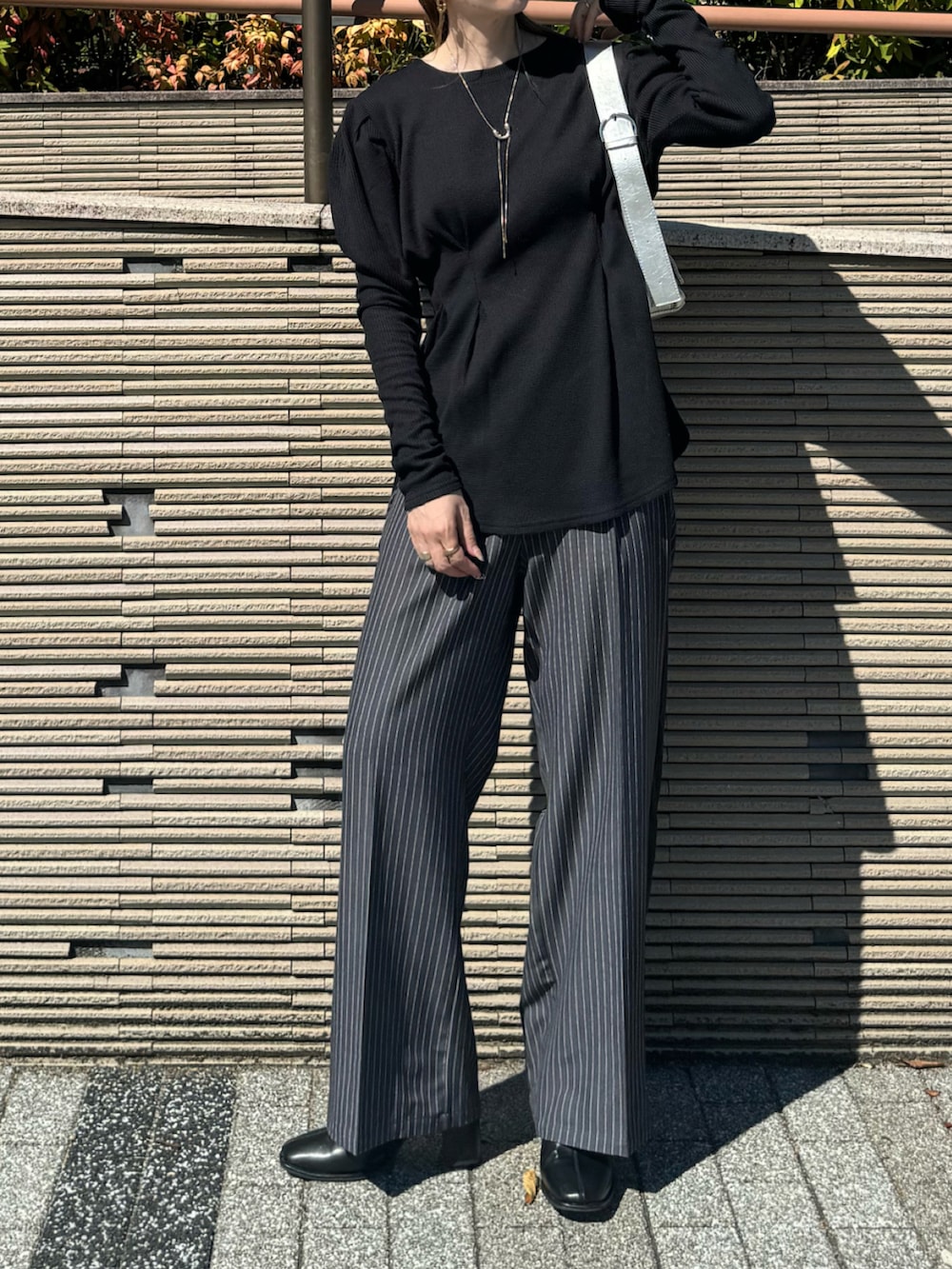 ブラック系のTシャツ/カットソー、シルバー系のショルダーバッグ、グレー系のスラックスを着用したレディースの秋コーディネートの3枚目の写真