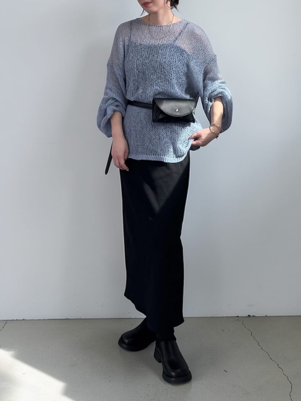 ブラック系のボディバッグ/ウエストポーチ、ブルー系のニット/セーター、ブラック系のワンピースを着用したレディースの春コーディネートの4枚目の写真