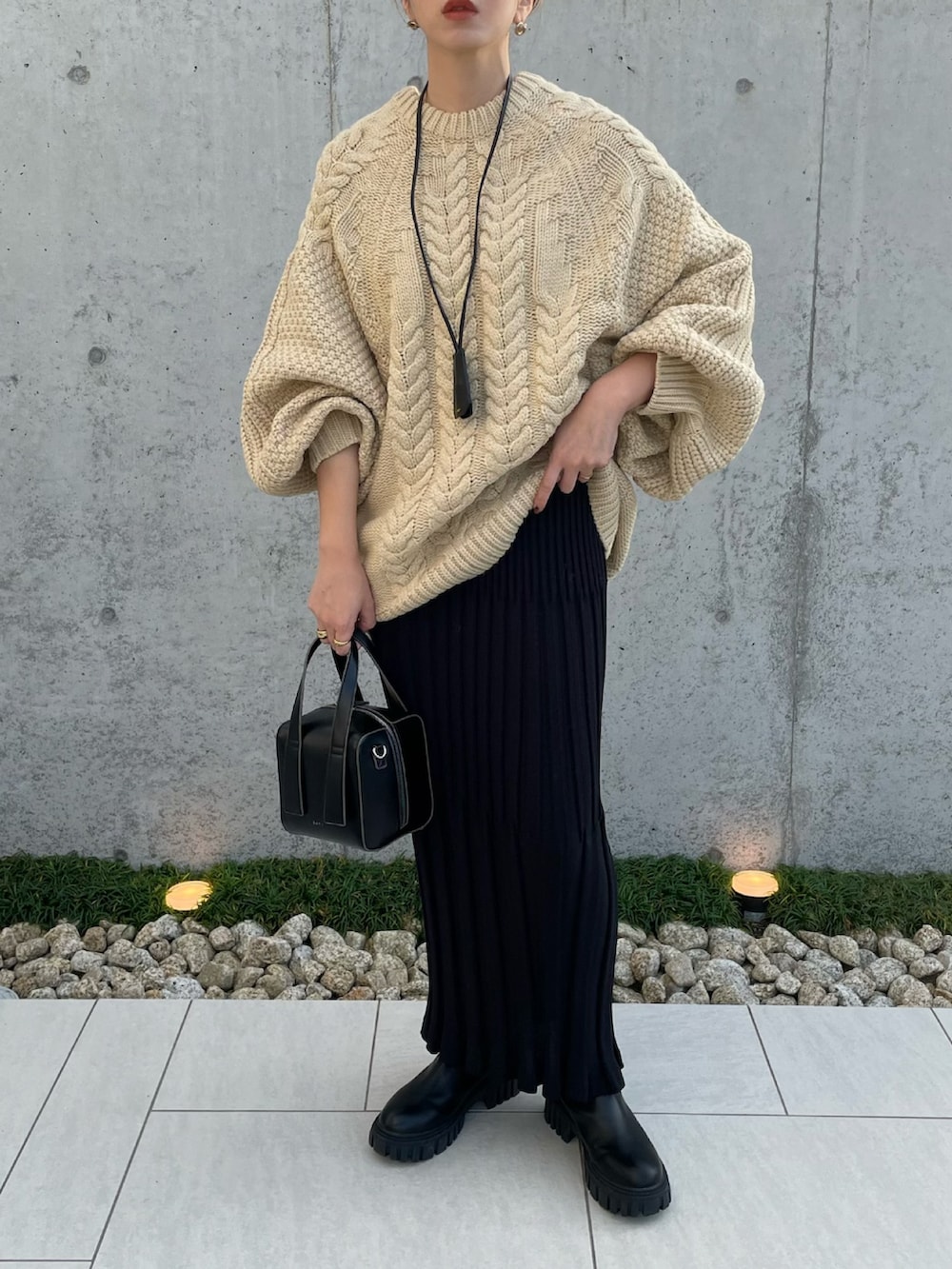 ホワイト系のニット/セーター、ブラック系のスカート、ブラック系のブーツを着用したレディースの秋コーディネートの3枚目の写真