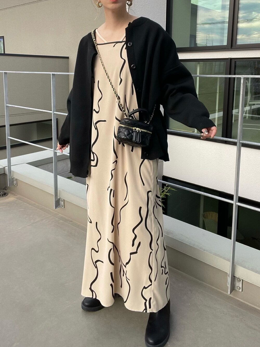 ブラック系のカーディガン/ボレロ、ホワイト系のワンピース、ブラック系のブーツを着用したレディースの秋コーディネートの5枚目の写真