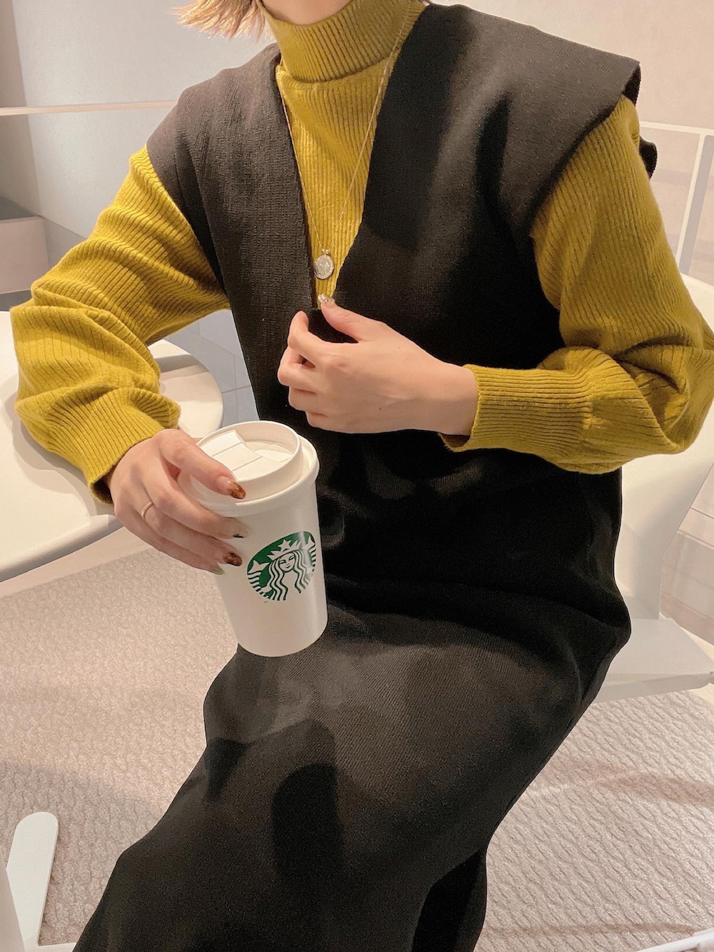 ブラック系のワンピース、グリーン系のニット/セーター、ゴールド系のネックレスを着用したレディースの冬コーディネートの2枚目の写真