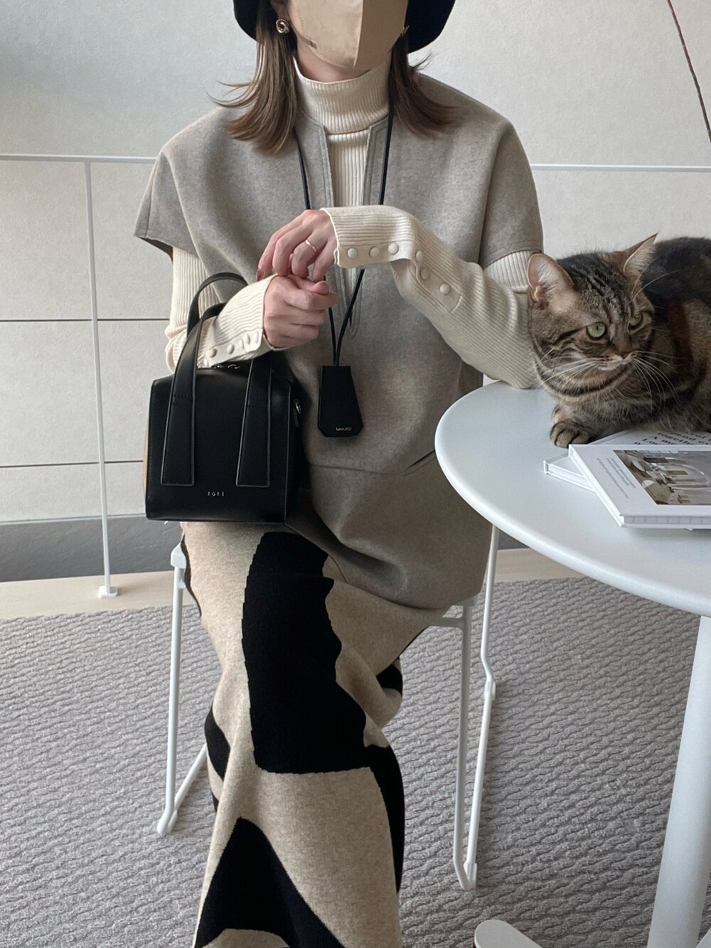 ベージュ系のベスト、ベージュ系のスカート、ブラック系のブーツを着用したレディースの秋コーディネートの5枚目の写真