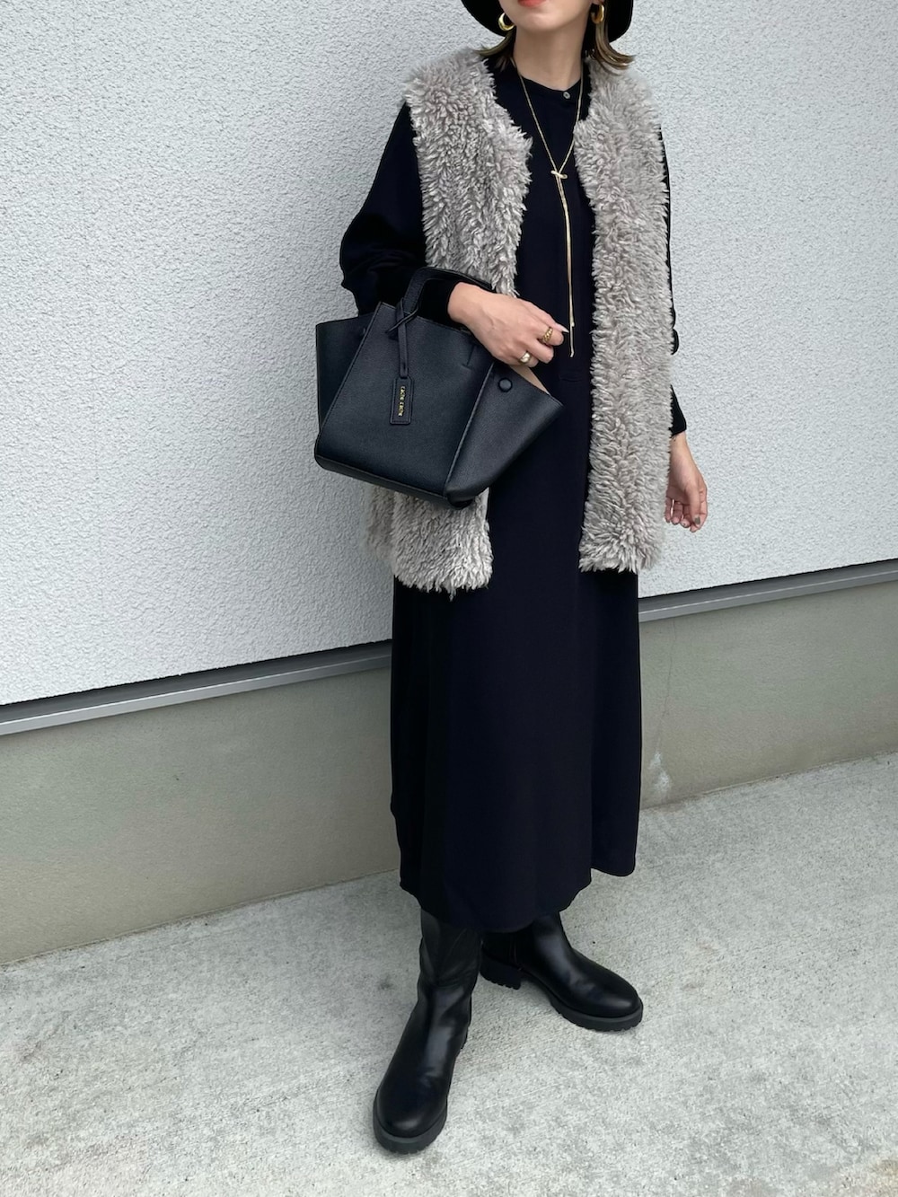 ブラック系のワンピース、ブラック系のハンドバッグ、ブラック系のブーツを着用したレディースの秋コーディネートの2枚目の写真