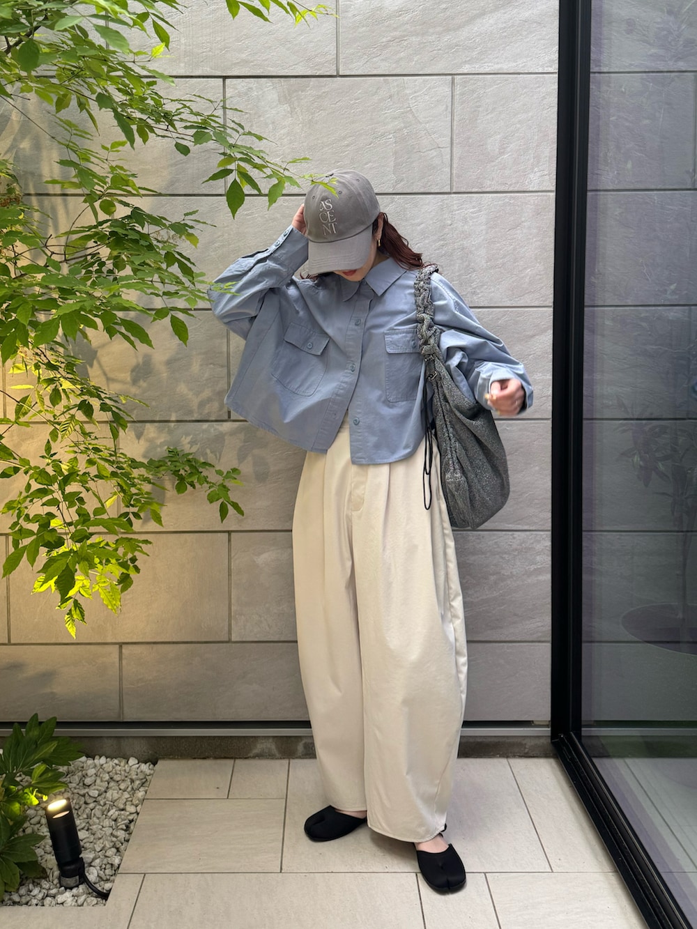 ホワイト系のチノパンツ、ブラック系のサンダル、シルバー系のトートバッグを着用したレディースの春コーディネートの2枚目の写真