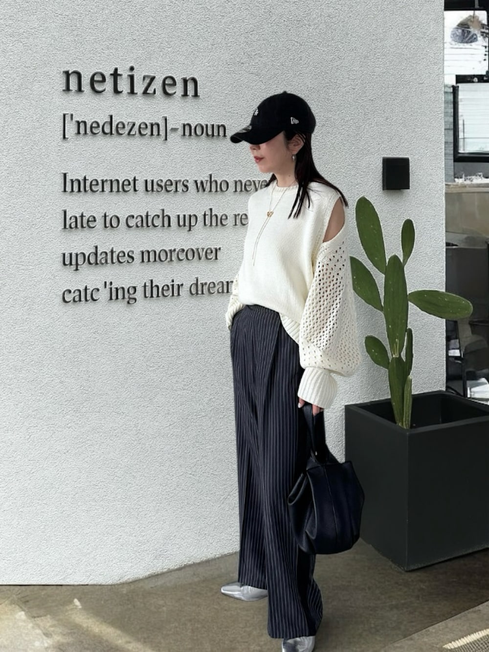 ホワイト系のニット/セーター、グレー系のスラックス、シルバー系のパンプスを着用したレディースの春コーディネートの3枚目の写真