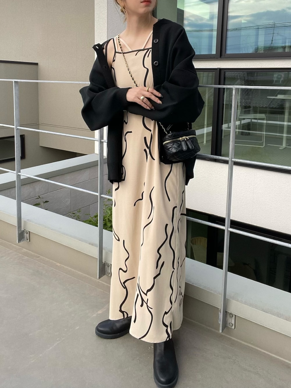 ブラック系のカーディガン/ボレロ、ホワイト系のワンピース、ブラック系のブーツを着用したレディースの秋コーディネートの3枚目の写真