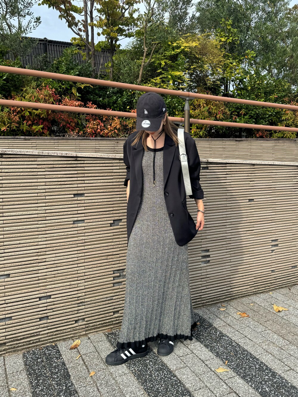 ブラック系のテーラードジャケット、ブラック系のワンピース、ブラック系のスニーカーを着用したレディースの秋コーディネートの2枚目の写真