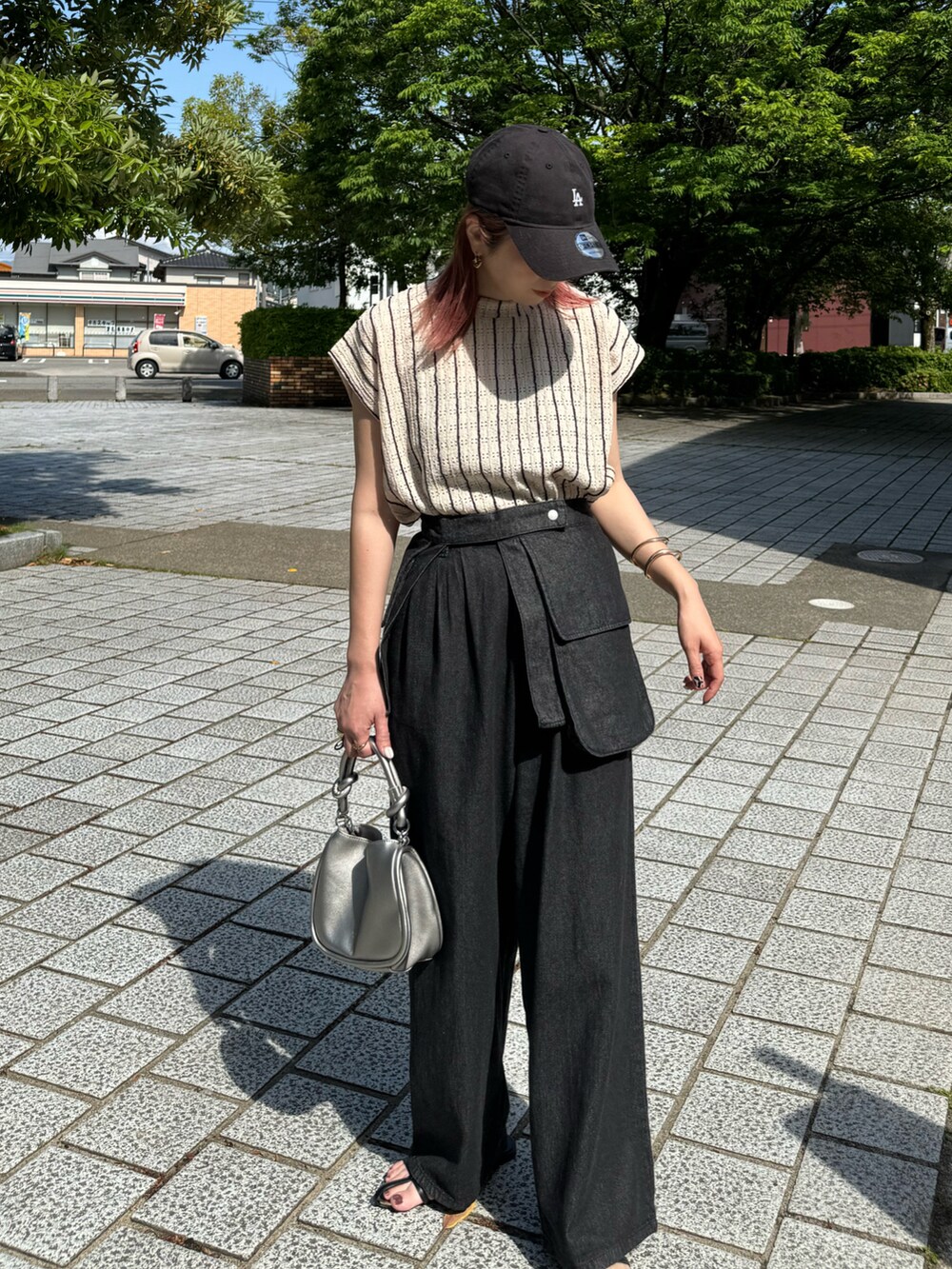 ブラック系のデニムパンツ、ブラック系のサンダル、シルバー系のショルダーバッグを着用したレディースの春コーディネートの2枚目の写真