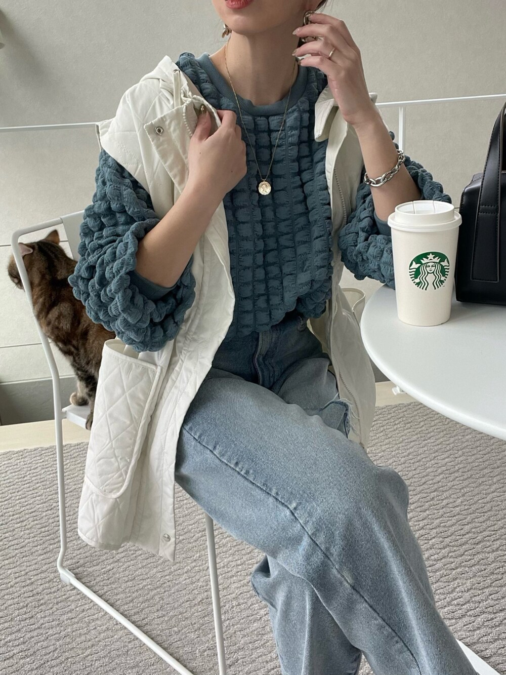 ブルー系のTシャツ/カットソー、ホワイト系のベスト、ブラック系のボストンバッグを着用したレディースの冬コーディネートの3枚目の写真