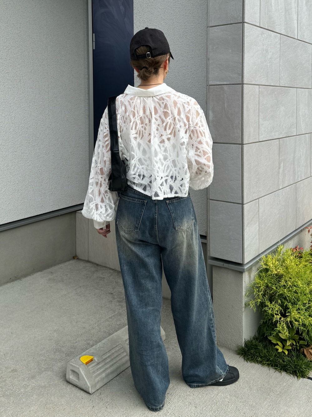 ブルー系のデニムパンツ、ブラック系のショルダーバッグ、ブラック系のスニーカーを着用したレディースの夏コーディネートの3枚目の写真