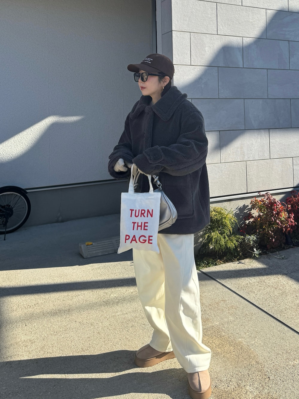 グレー系のステンカラーコート、ホワイト系のスウェットパンツ、ブラウン系のキャップを着用したレディースの冬コーディネートの2枚目の写真
