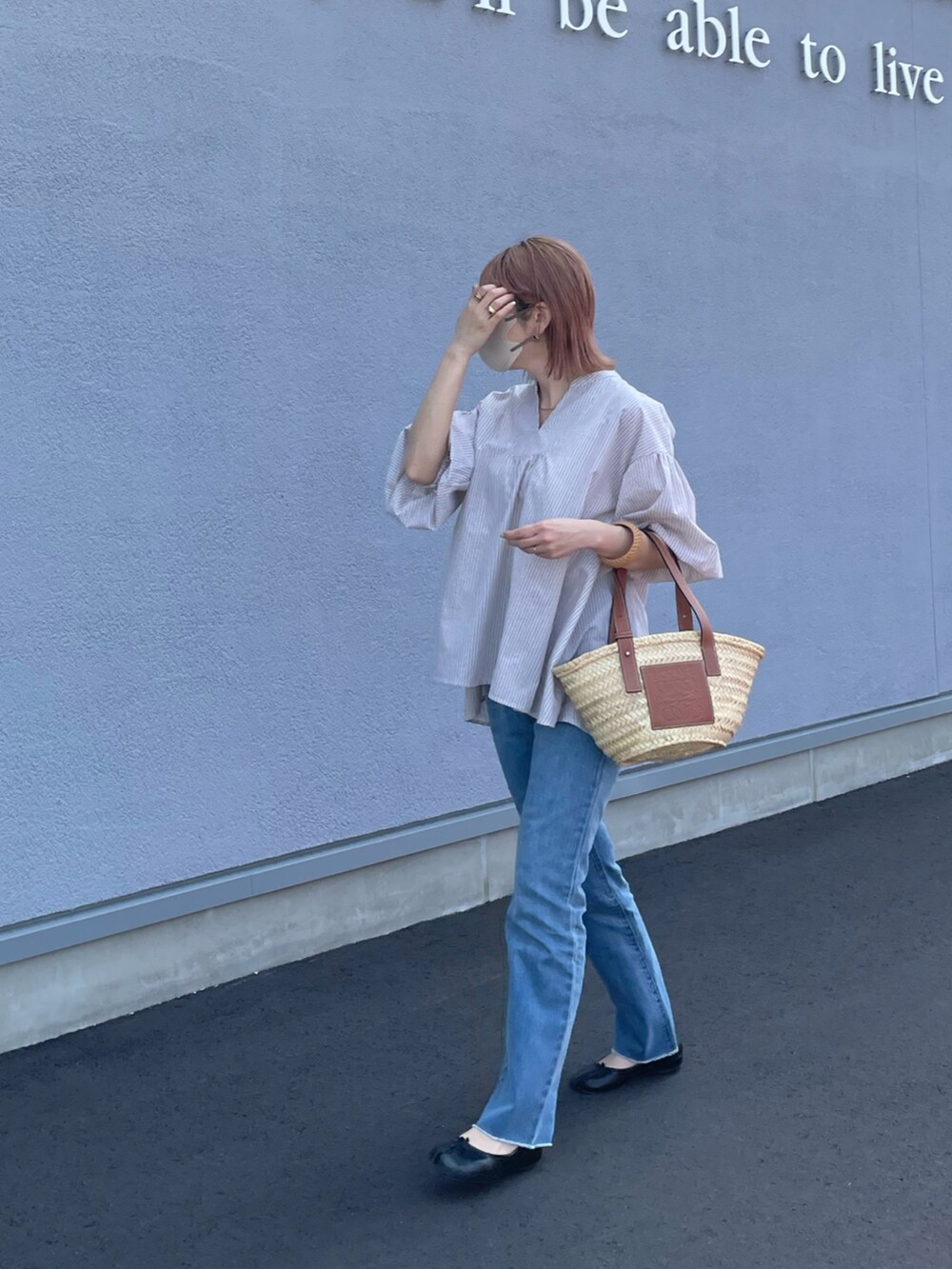 ベージュ系のシャツ/ブラウス、ブラウン系のトートバッグ、ブルー系のデニムパンツを着用したレディースの春コーディネートの2枚目の写真