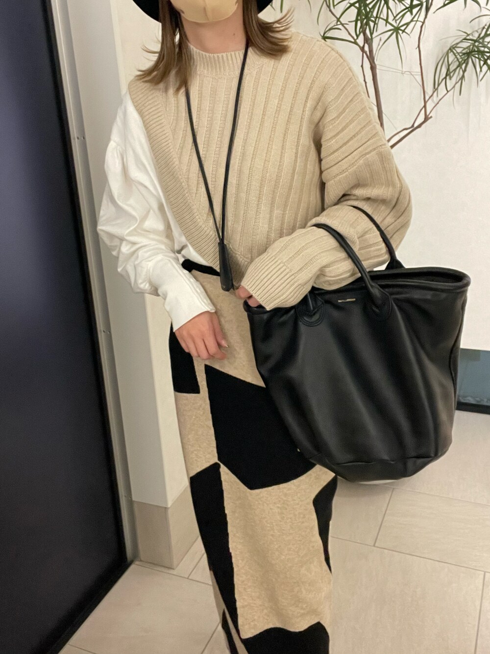 ホワイト系のTシャツ/カットソー、ベージュ系のスカート、ブラック系のブーツを着用したレディースの冬コーディネートの3枚目の写真