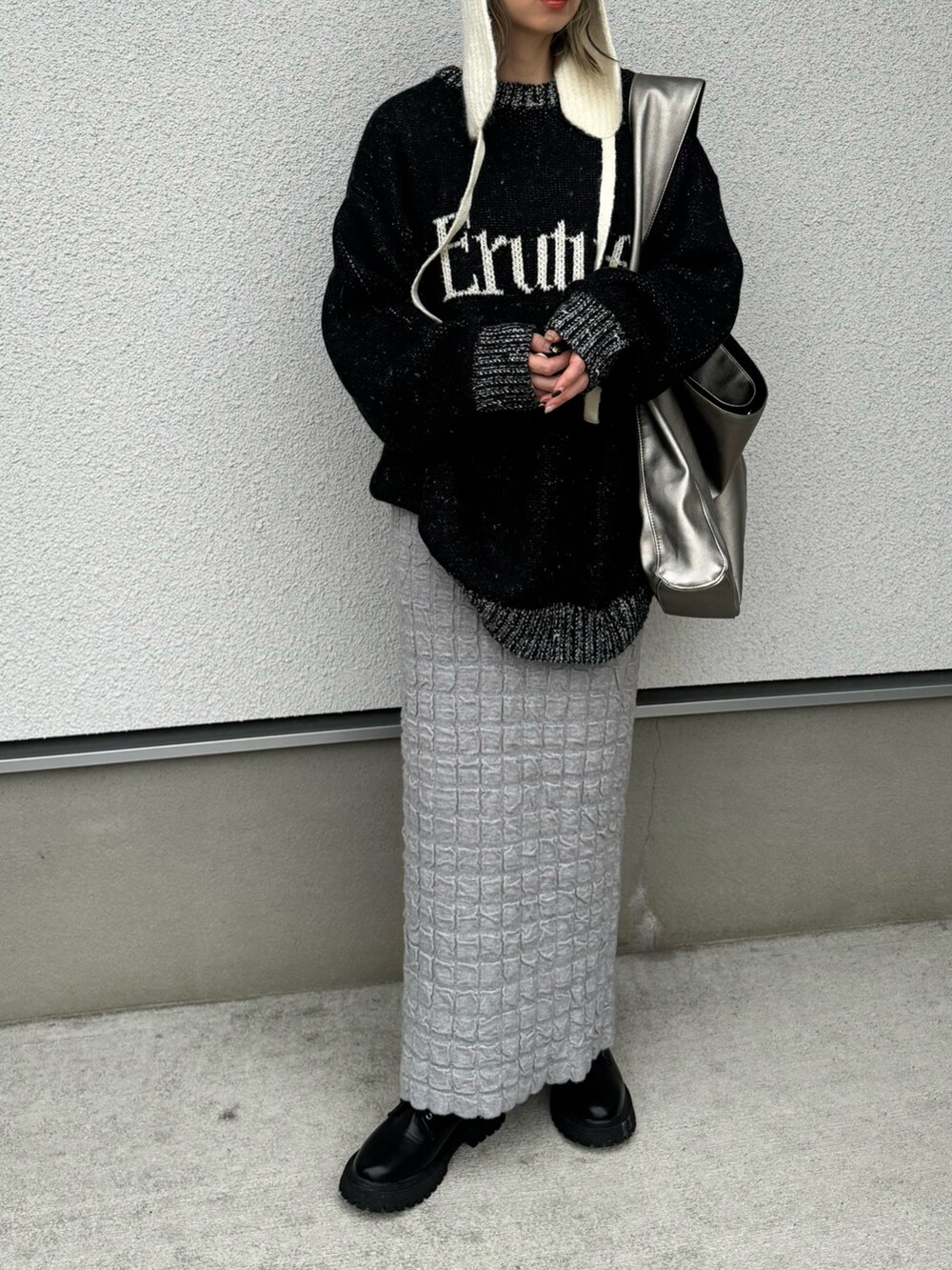 ブラック系のニット/セーター、シルバー系のトートバッグ、ブラック系のブーツを着用したレディースの冬コーディネートの2枚目の写真