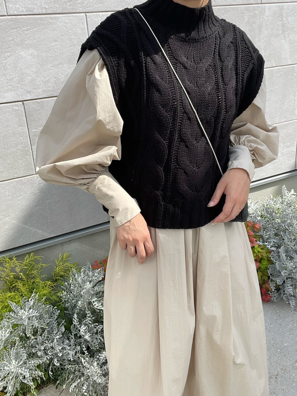 ブラック系のベスト、ベージュ系のワンピース、ブラック系のショルダーバッグを着用したレディースの秋コーディネートの4枚目の写真