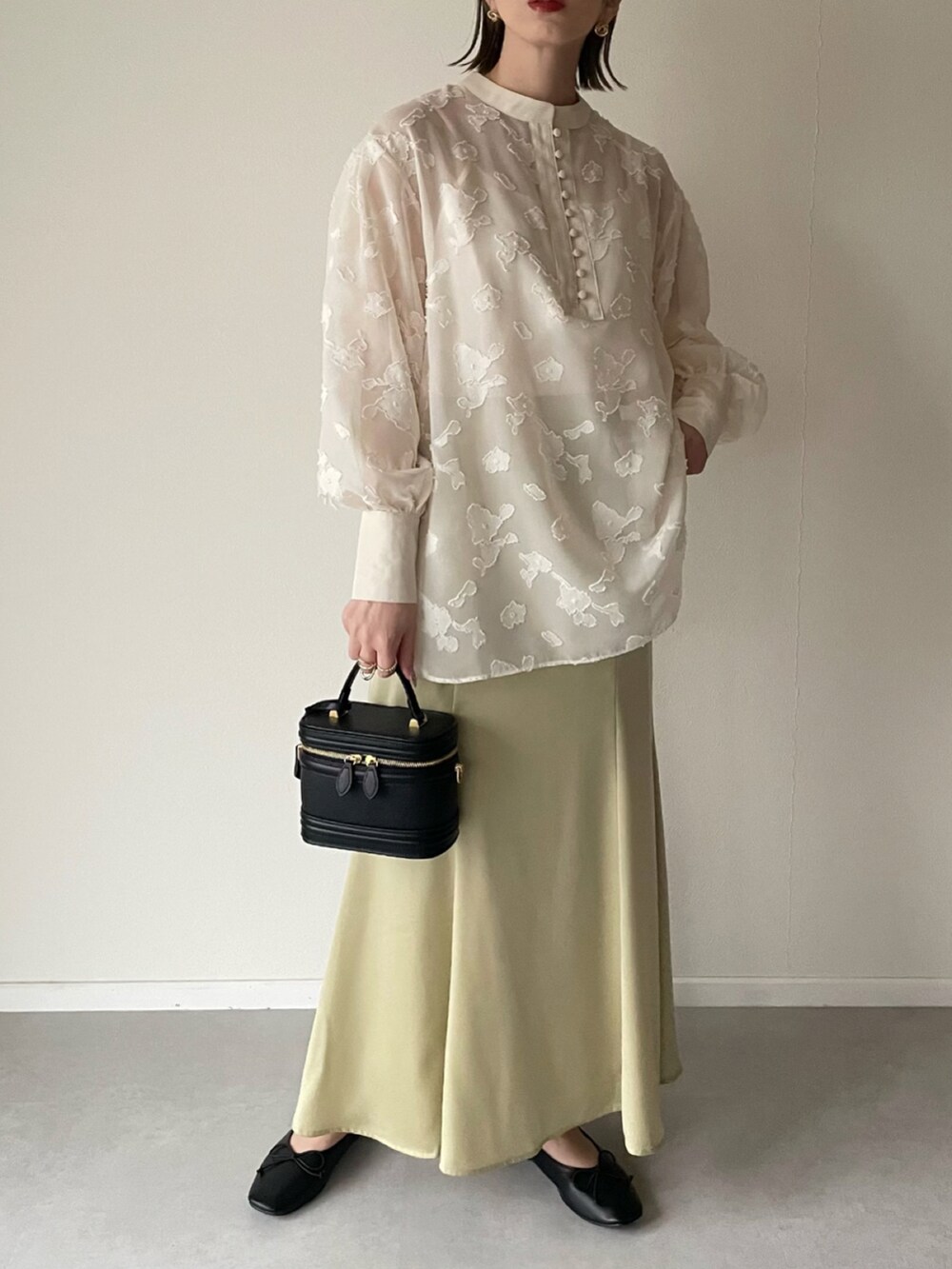 ホワイト系のシャツ/ブラウス、イエロー系のスカート、ブラック系のパンプスを着用したレディースの春コーディネートの3枚目の写真