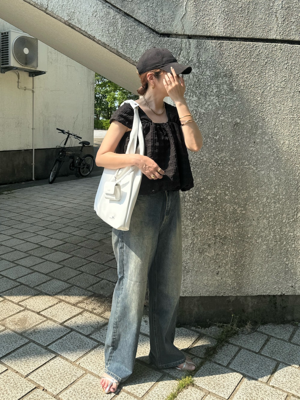 ホワイト系のトートバッグ、ブルー系のデニムパンツ、シルバー系のサンダルを着用したレディースの夏コーディネートの5枚目の写真