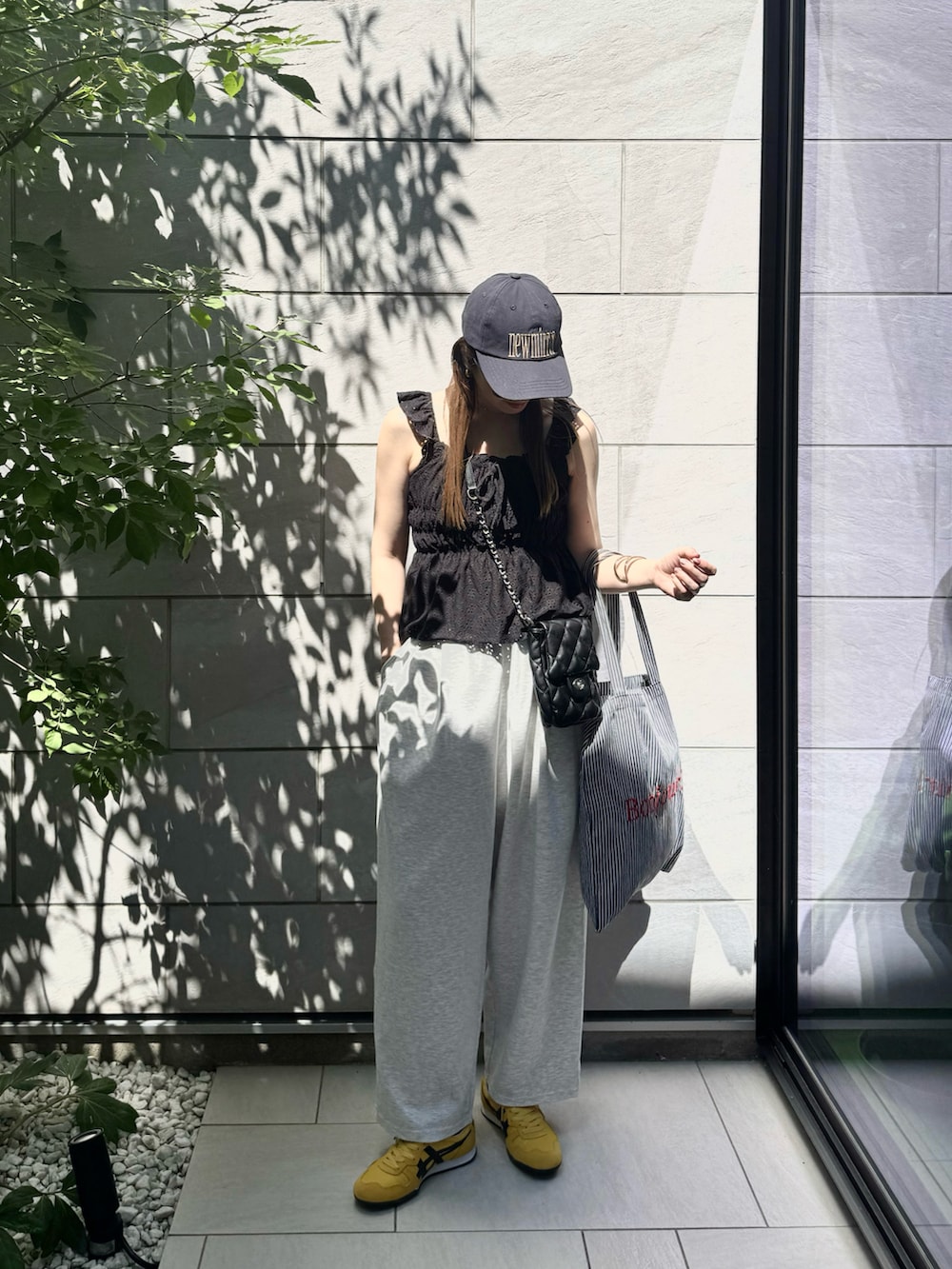 グレー系のデニムパンツ、ブラック系のトートバッグ、イエロー系のスニーカーを着用したレディースの秋コーディネートの2枚目の写真