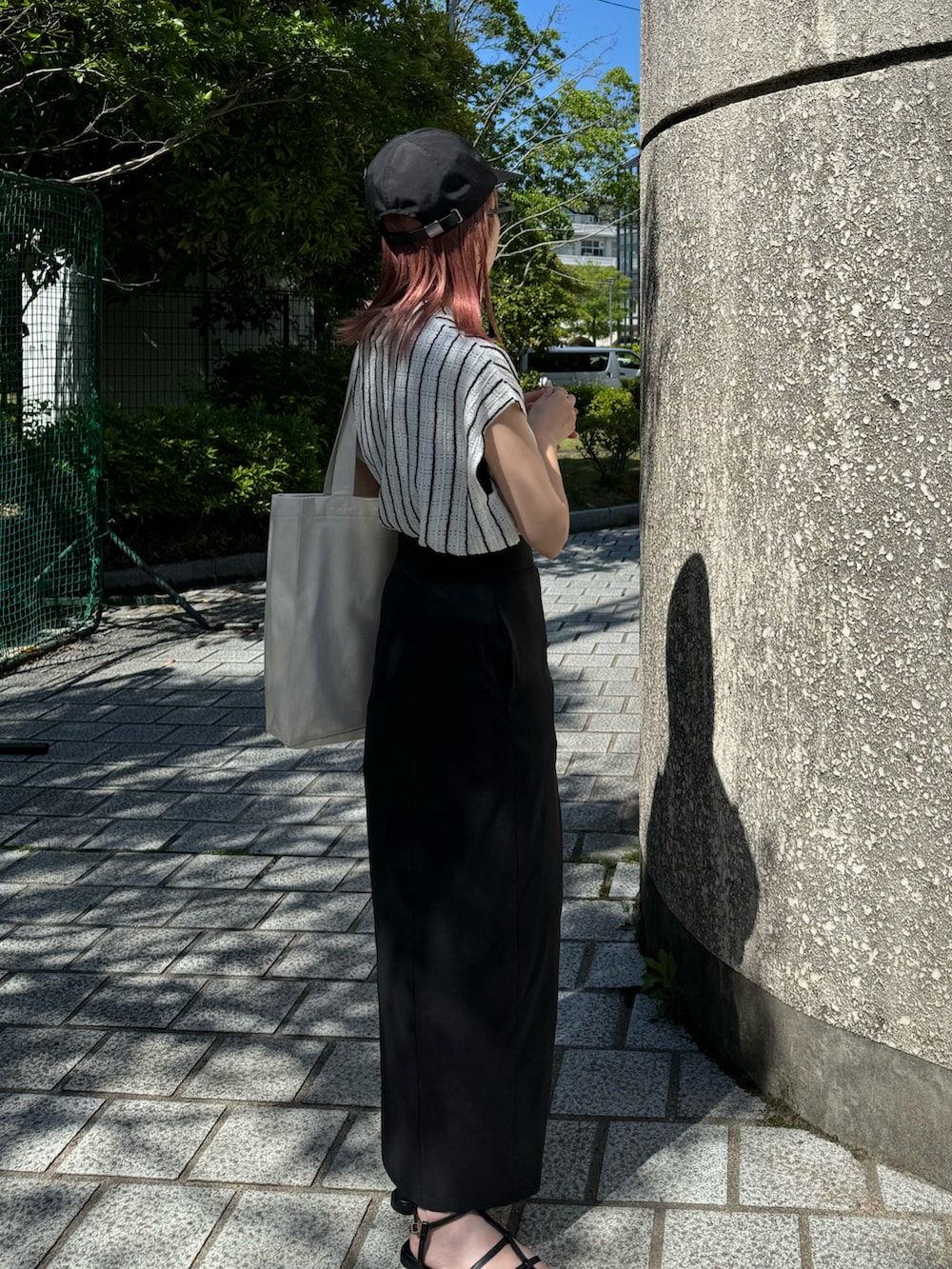ブラック系のサンダル、ホワイト系のニット/セーター、ブラック系のスカートを着用したレディースの夏コーディネートの2枚目の写真