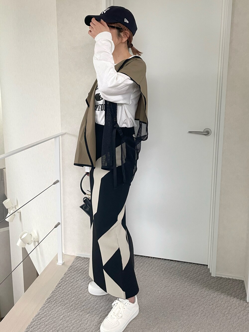 グリーン系のベスト、ホワイト系のTシャツ/カットソー、ホワイト系のスニーカーを着用したレディースの春コーディネートの2枚目の写真