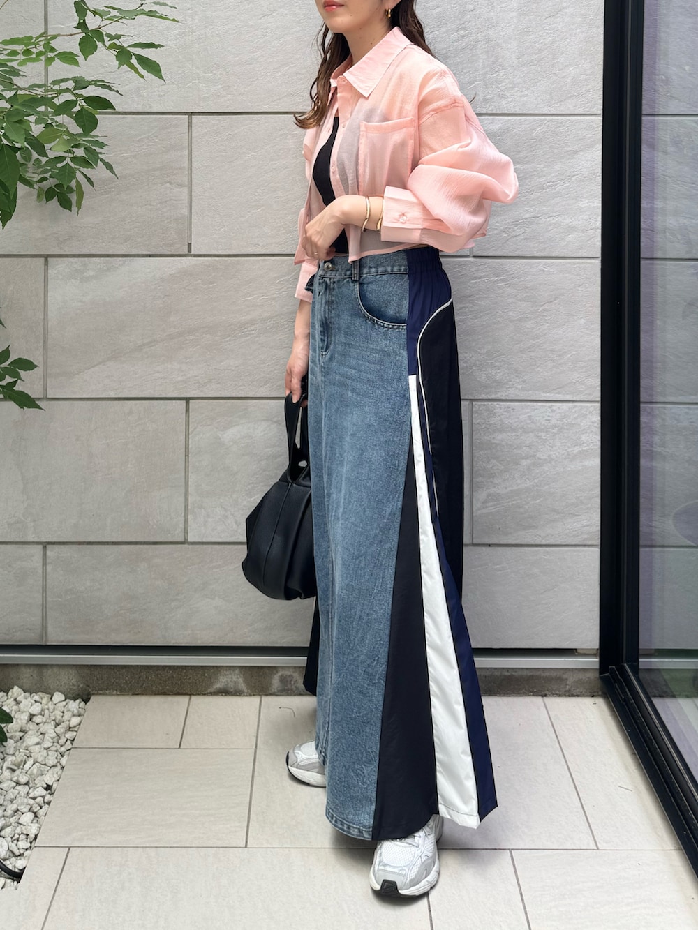 ブラック系のハンドバッグ、ブルー系のスカート、グレー系のスニーカーを着用したレディースの夏コーディネートの4枚目の写真