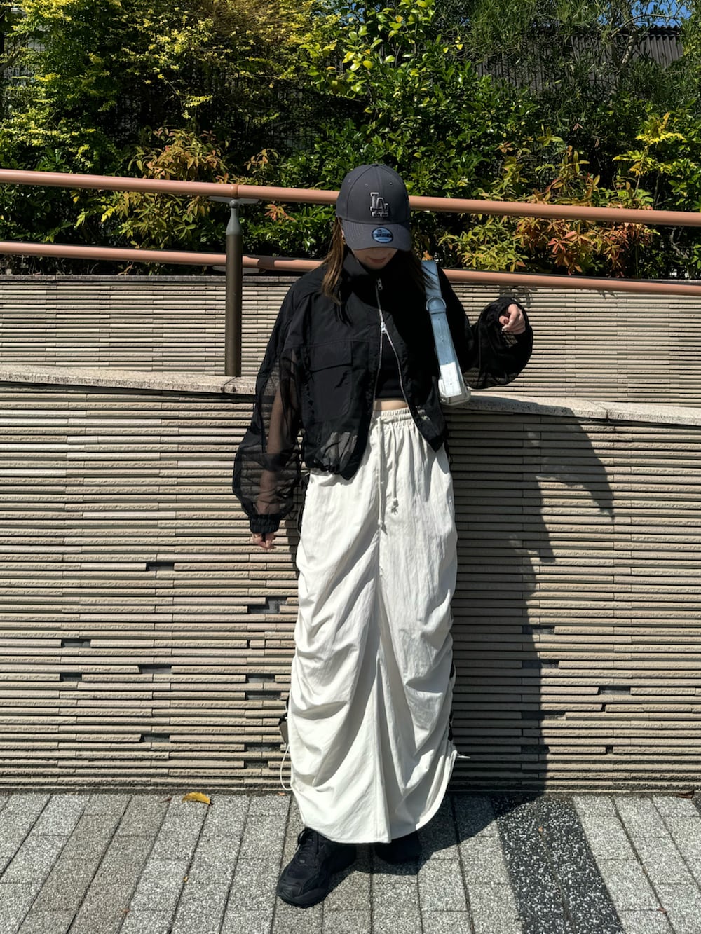 ホワイト系のスカート、ブラック系のブルゾン、シルバー系のショルダーバッグを着用したレディースの秋コーディネートの5枚目の写真