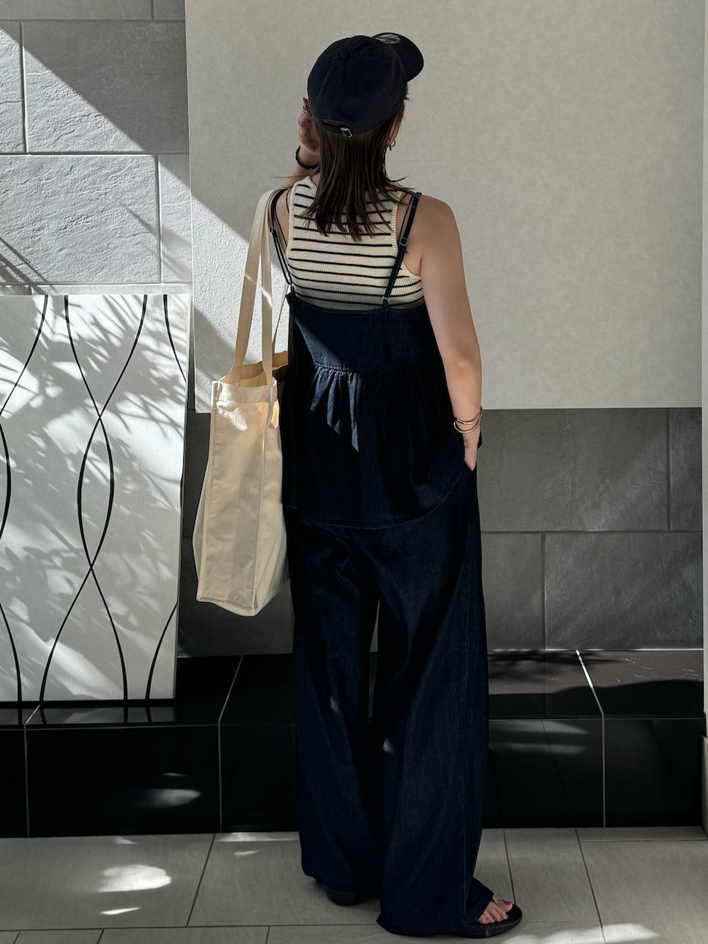 ブルー系のキャミソール、ブルー系のデニムパンツ、ホワイト系のトートバッグを着用したレディースの夏コーディネートの5枚目の写真