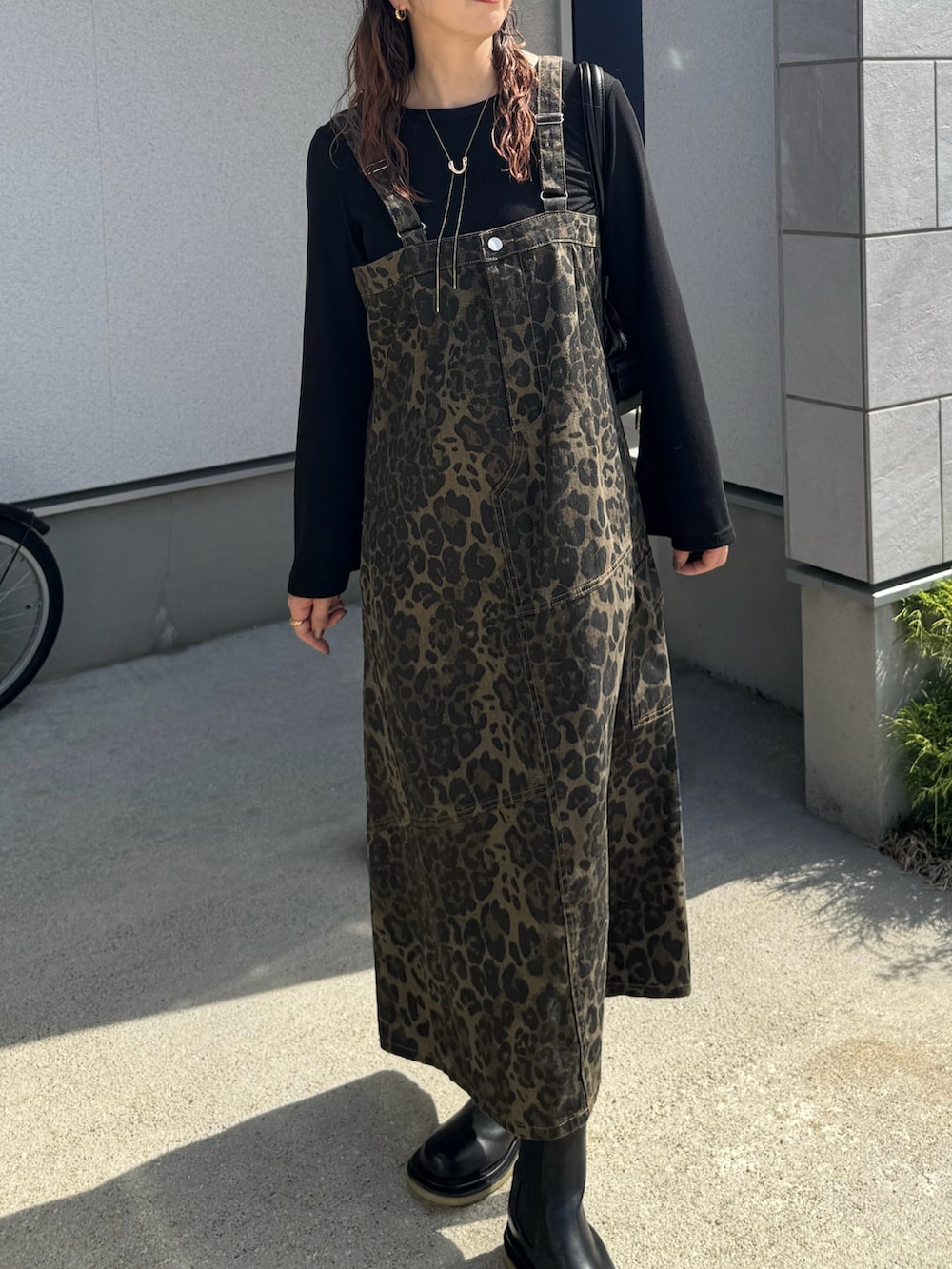 ブラック系のボストンバッグ、ブラック系のブーツ、ブラウン系のキャップを着用したレディースの秋コーディネートの2枚目の写真