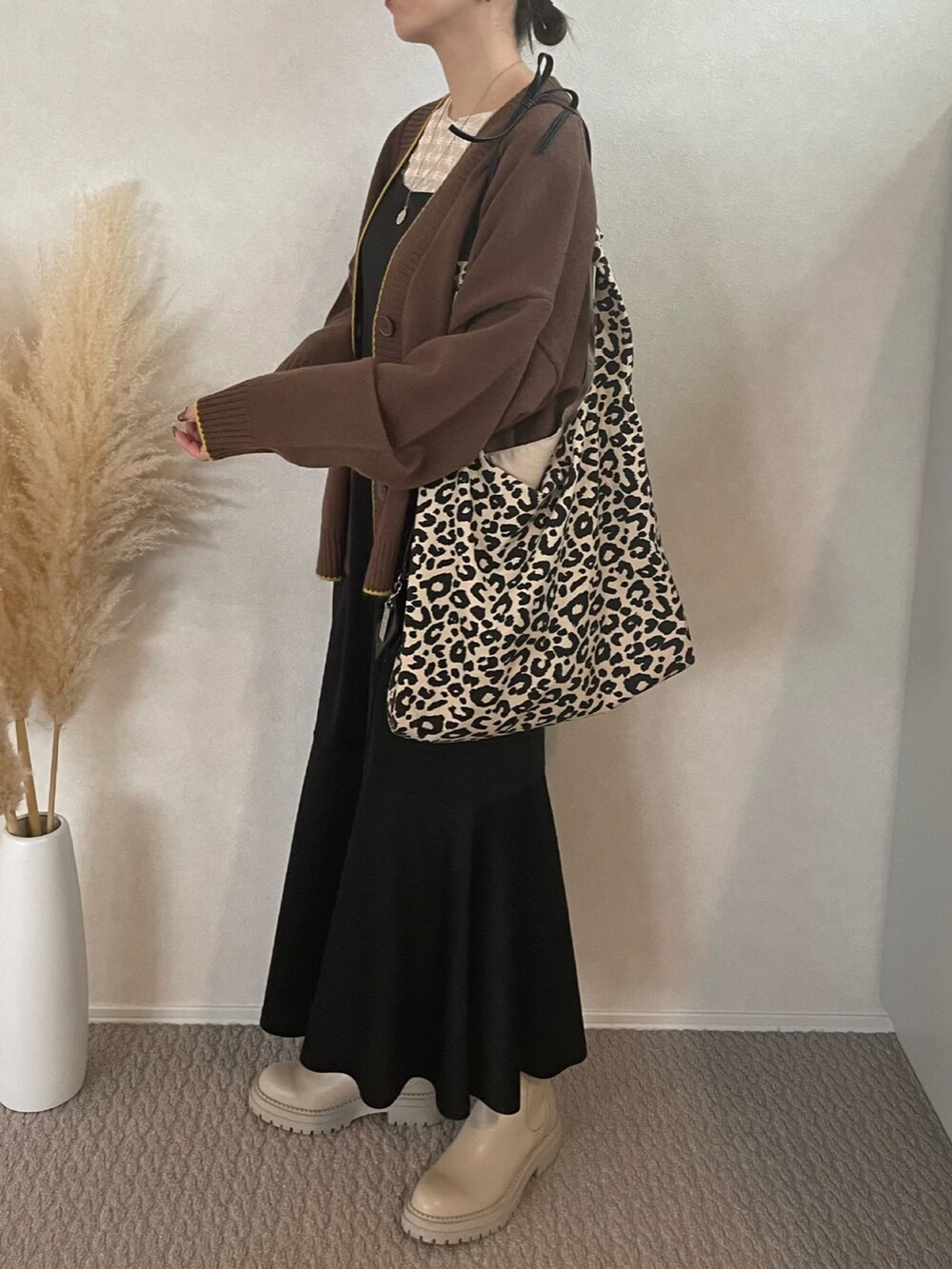 ブラウン系のカーディガン/ボレロ、ブラック系のワンピース、ホワイト系のブーツを着用したレディースの冬コーディネートの2枚目の写真