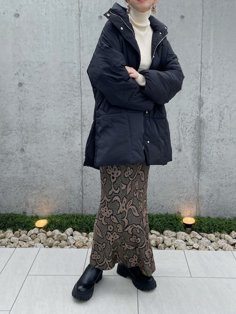 ブラック系のダウンジャケット/コート、ホワイト系のニット/セーター、ブラック系のブーツを着用したレディースの秋コーディネートの2枚目の写真