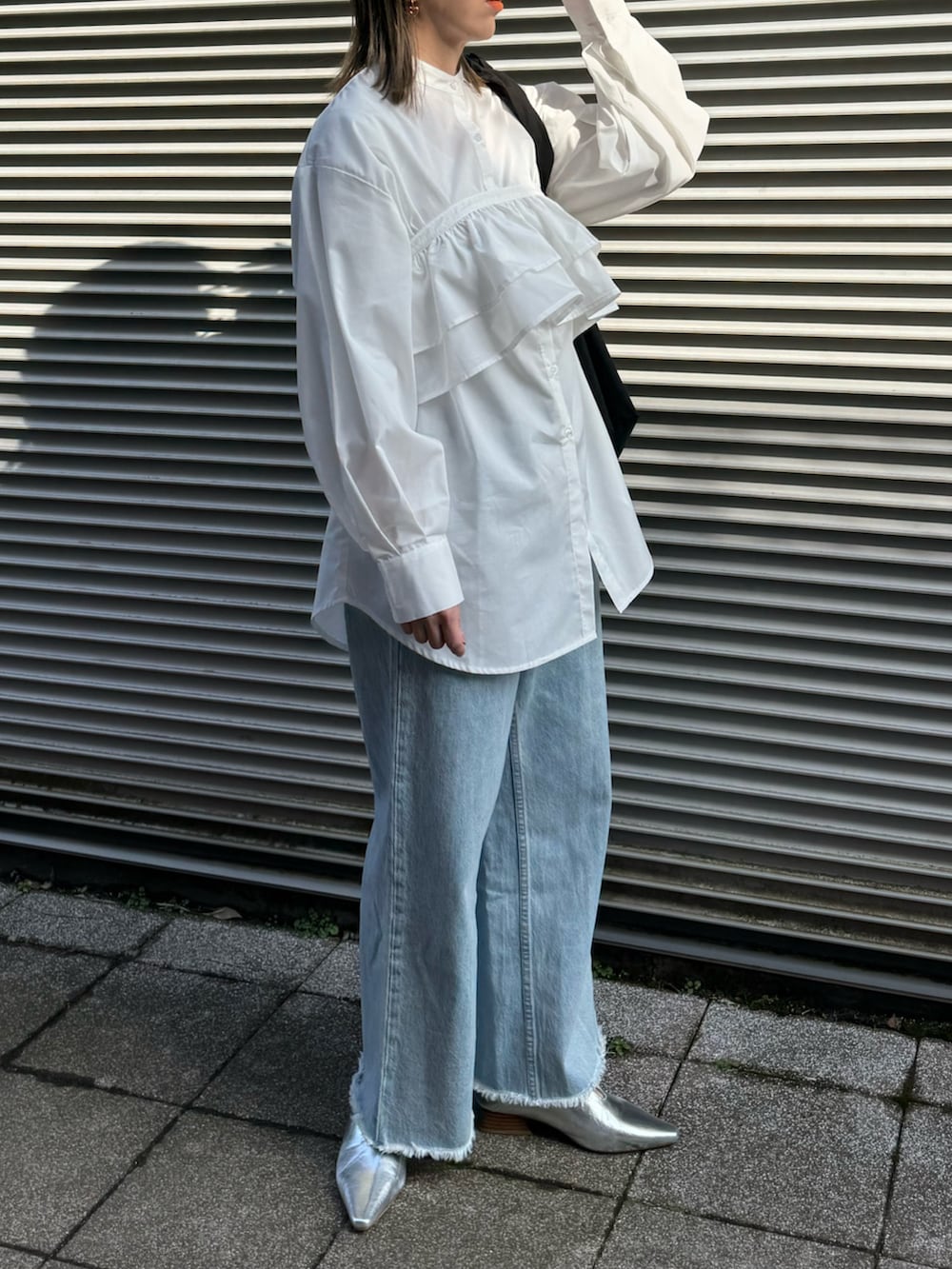 ホワイト系のシャツ/ブラウス、シルバー系のパンプス、ブルー系のデニムパンツを着用したレディースの冬コーディネートの2枚目の写真