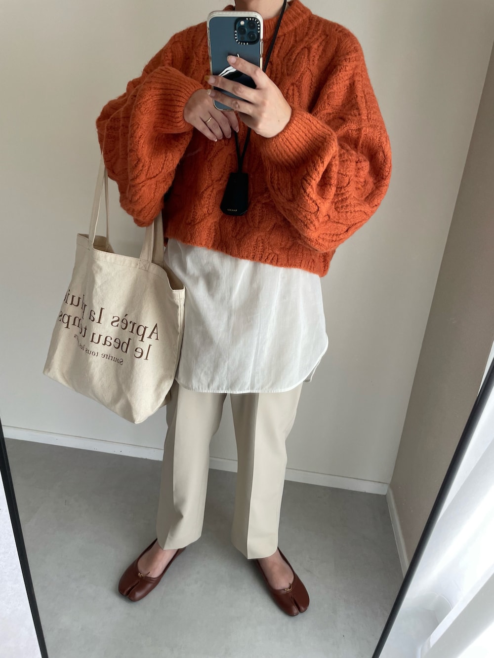 オレンジ系のニット/セーター、ベージュ系のその他パンツ、ブラウン系のパンプスを着用したレディースの秋コーディネートの2枚目の写真