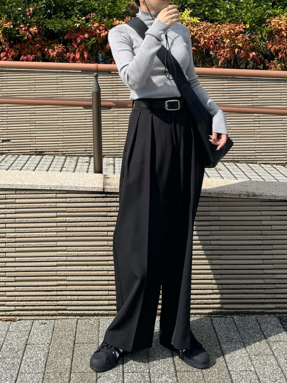 グレー系のニット/セーター、ブラック系のその他パンツ、ブラック系のスニーカーを着用したレディースの秋コーディネートの3枚目の写真