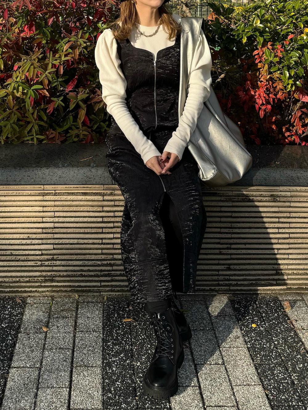 ブラック系のジャンパースカート、ホワイト系のTシャツ/カットソー、ブラック系のブーツを着用したレディースの秋コーディネートの5枚目の写真