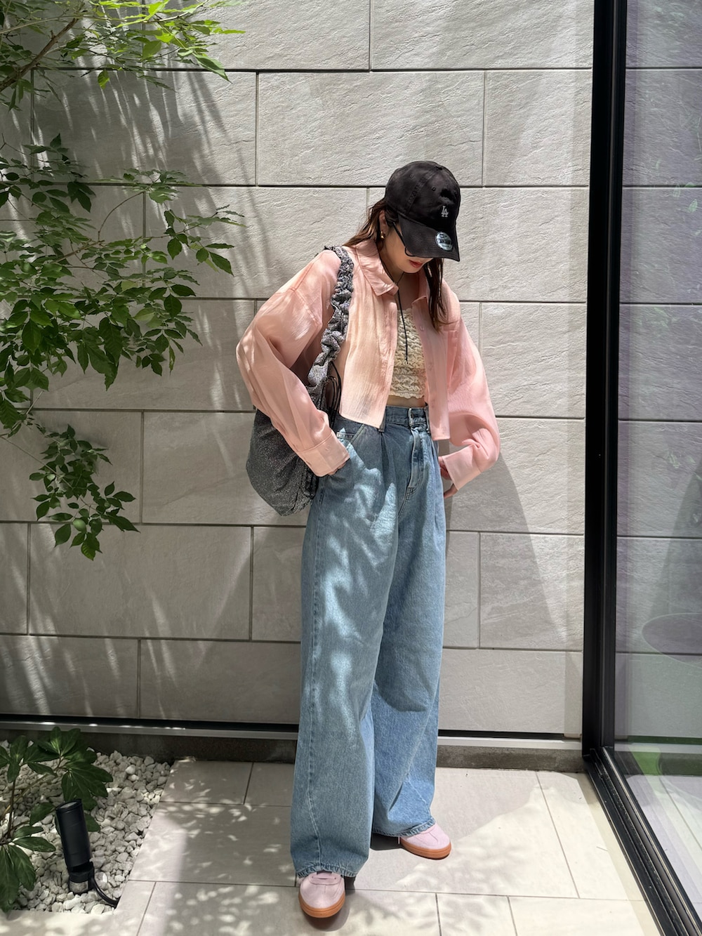 ホワイト系のタンクトップ、ブルー系のデニムパンツ、シルバー系のトートバッグを着用したレディースの夏コーディネートの2枚目の写真