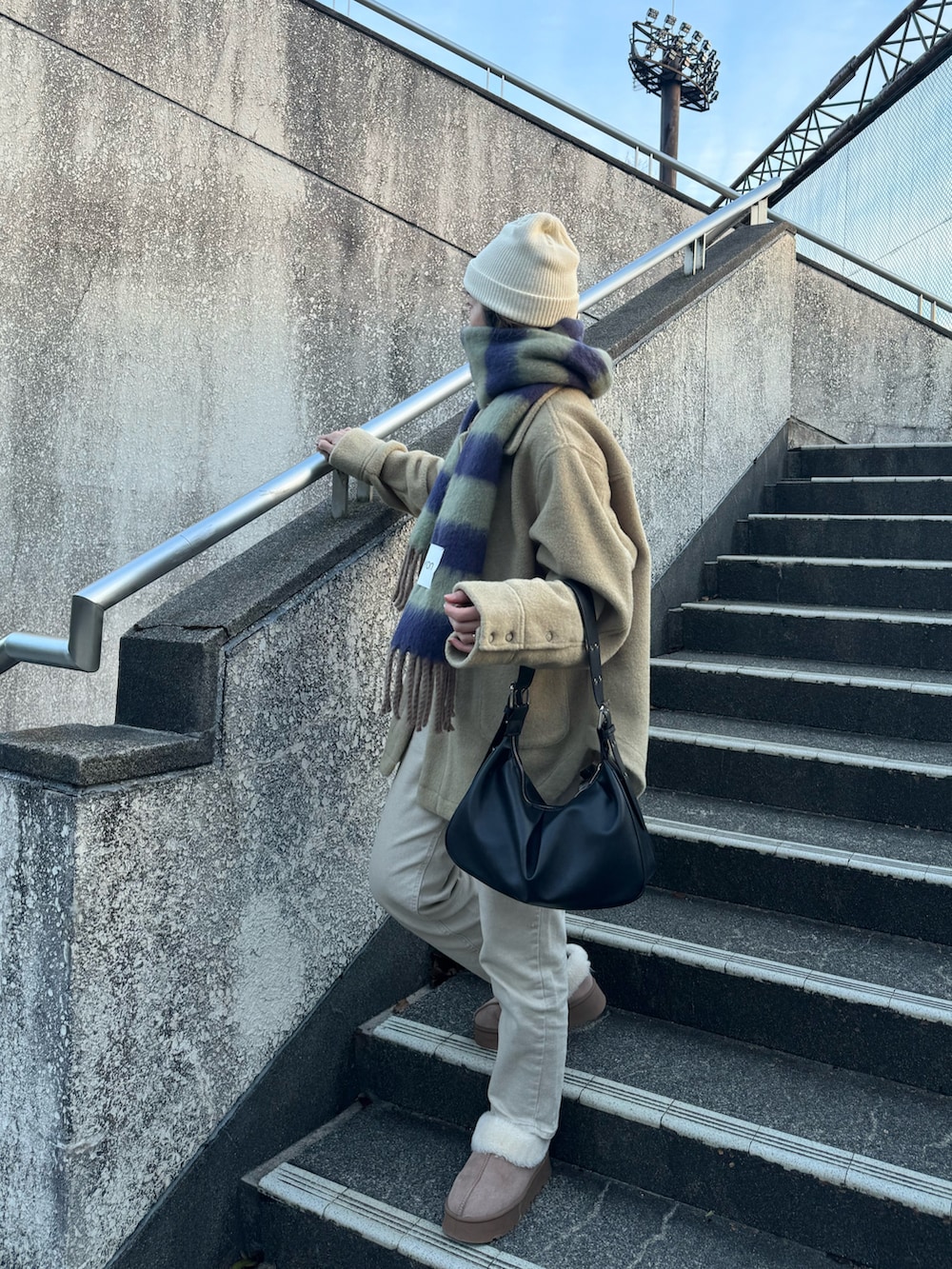 ブラック系のハンドバッグ、グリーン系のその他アウター、グリーン系のマフラーを着用したレディースの冬コーディネートの2枚目の写真